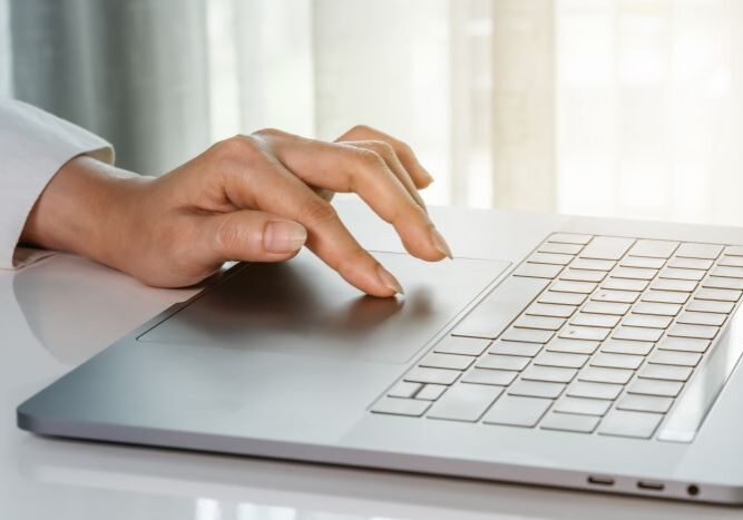 close-up female hand touching touchpad on laptop computer